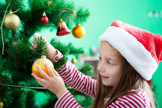 Cute little girl in Santa hat with Christmas decoration