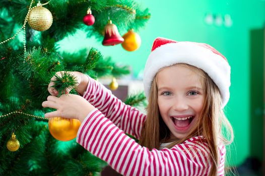 Smiling little girl in red Santa hat with Christmas decoration