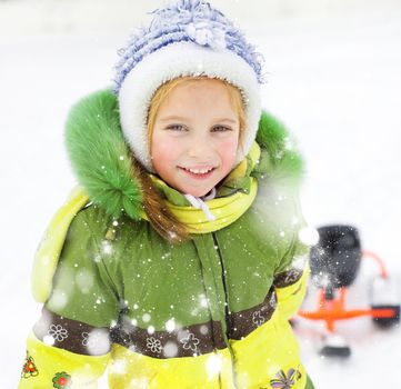 Portrait of Happy litte girl with children's snowmobile