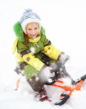 Smiling Happy litte girl with children's snowmobile