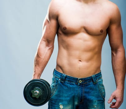 Muscular man with weights on a gray background