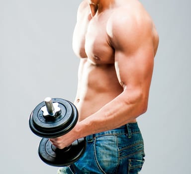 Muscular man with dumbbells on a gray background