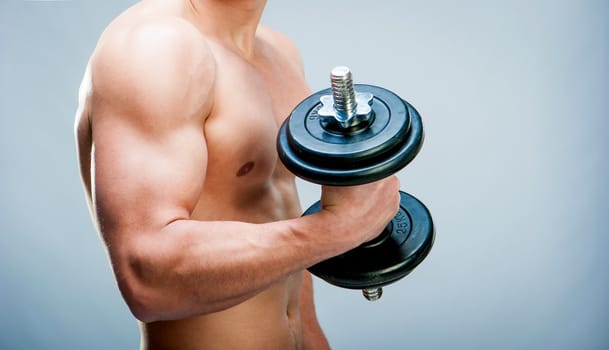 Torso Muscular man with dumbbells on a gray background