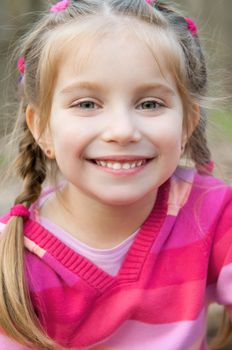 cute little girl smiling in a park close-up