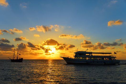 Sunrise in San Andres, Colombia over an old pirate ship and a modern ship