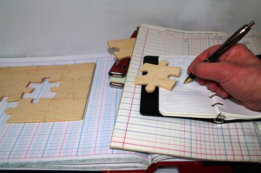 Book Keeping Puzzle with hand with pieces hidden in the booking material