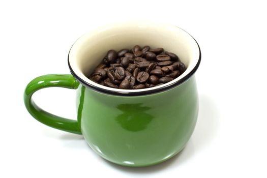 A green cup and coffee beans on white background