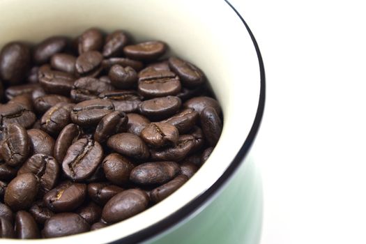 A green cup and coffee beans on white background