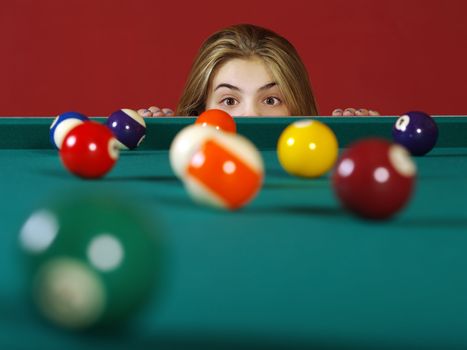 Photo of a young girl checking the billiard balls for a chance at a good shot.