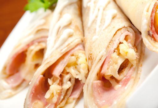 rolled pancakes stuffed ham and cheese. Shallow depth-of-field.