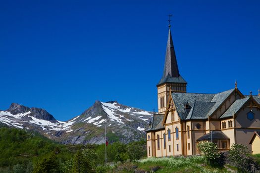 Scenic Lofoten cathedral, famous landmark on Lofoten islands in Norway with snowy mountain peaks in the background