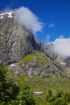 Towering rock face of mountain above road on Lofoten islands in Norway, popular tourist destination