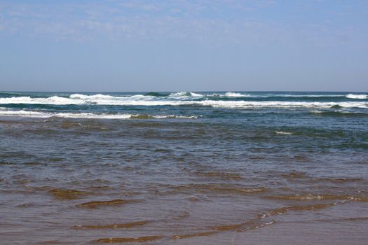 panoramic views of the ocean with its waves over a blue sky