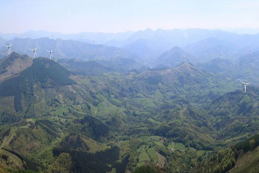 more wind turbines on mountain tops in aerial view of the horizon