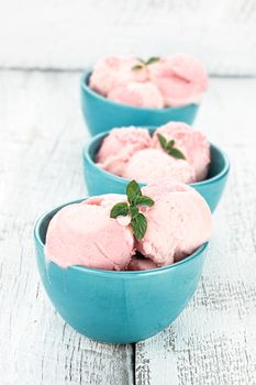 Three bowls of strawberry or raspberry sorbet in a row, garnished with fresh mint.
