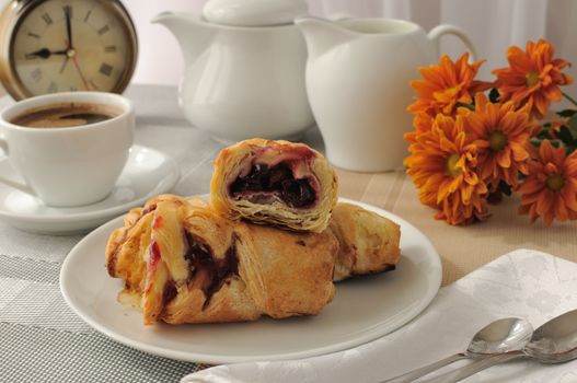 A piece of strudel with cherries with a morning cup of coffee