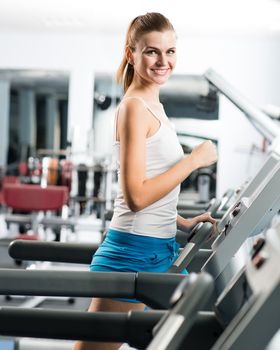 attractive young woman runs on a treadmill, is engaged in fitness sport club