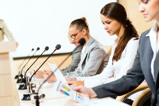 businessmen communicate at the conference, sitting at the table, on the table microphones and documents