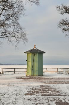 Green old pump house by the water a sunny winter day.
