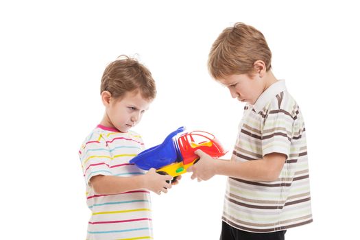 Two little displeased child boy brothers fighting for toy in family conflict