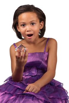 A young girl drops her jaw in awe whilst holding a large diamond in her hand.