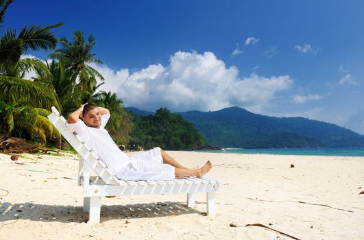 Man in white relaxing on a tropical beach