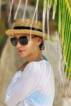 Woman in sunglasses near palm tree wearing hat