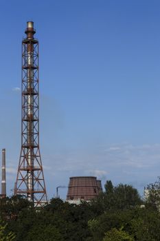 Chimney-stalk and other factory buildings on blue sky background.