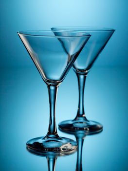 Two empty martini glasses on blue background