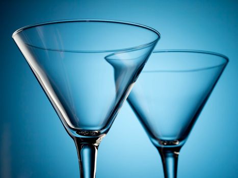 Two empty martini glasses on blue background