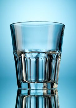 One empty tumbler glass on blue background