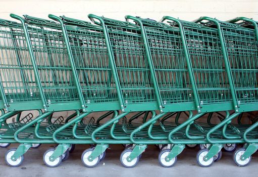 Green shopping carts together in a line up.