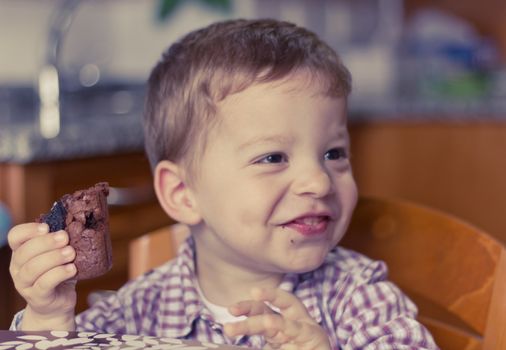 Little boy eating a piece of brownie with a cute smile