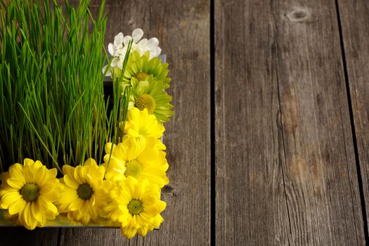Grass and flowers over wooden table