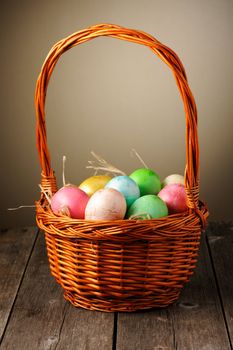 Colored easter eggs in basket on wooden table