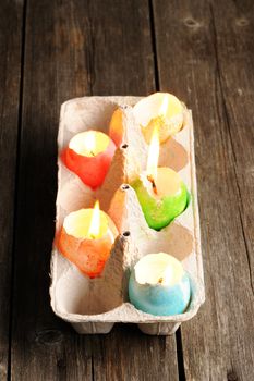 Colored easter eggs candles on wooden table