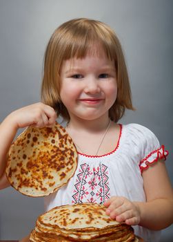 Russian little girl eats pancakes with red caviar.