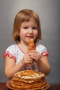 Russian little girl eats pancakes with red caviar.