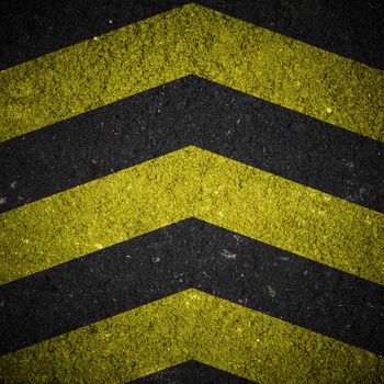 Yellow and black warning sign on asphalt texture