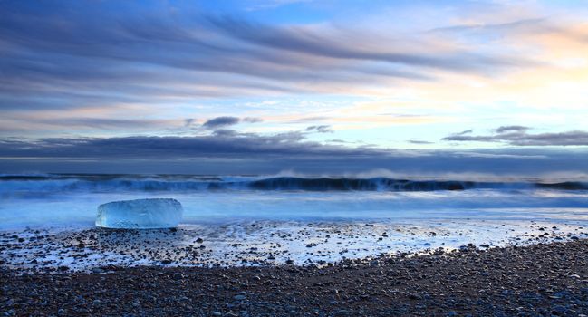 Iceburg on vocanic black sand beach at sunset in south Iceland