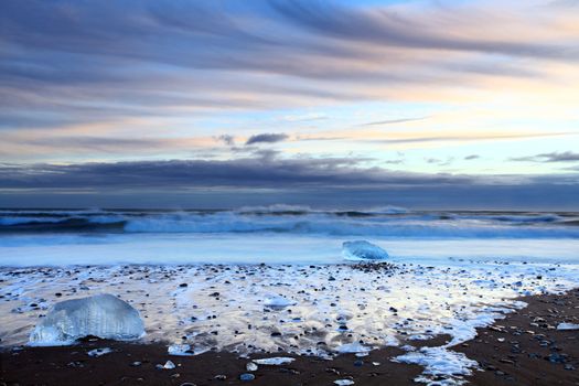 Iceburg on vocanic black sand beach at sunset in south Iceland