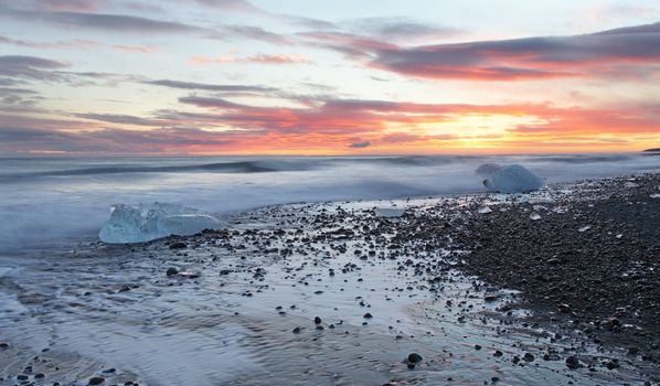 Iceburg on vocanic black sand beach at sunset in south Iceland