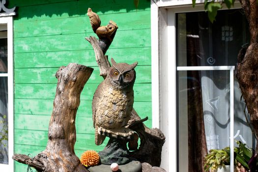 Wooden owl and squrrel in front of a cottage
