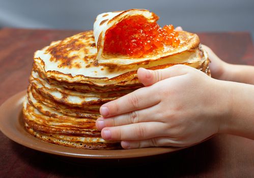 Traditional Russian pancakes  with red caviar.hands child