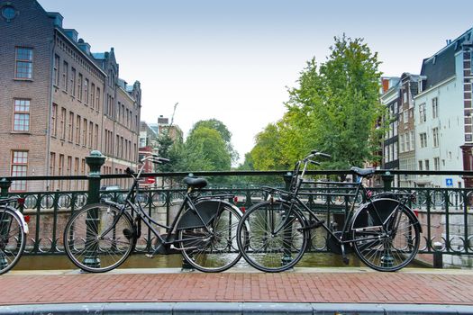 Couples of old black bikes in a bridge over the canal in Amsterdam.