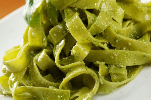 Tagliatelle pasta with pesto on light plate. closeup