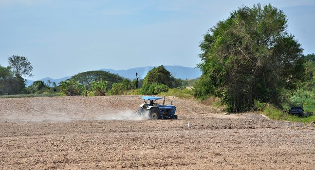 harvester filling a grain truck with farm yard in background 