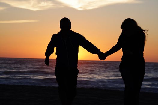 A couple on the beach with sunset background