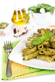 Pasta with pesto sauce and ingredients over white