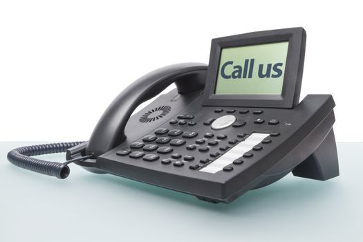 modern business voip phone on glass desk with the words - Call us - in the display